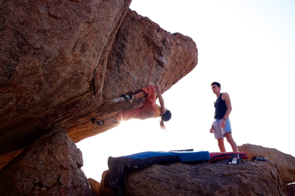 Bouldern am Fels, zwei Personen im Gegenlicht.